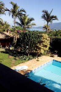 a swimming pool with palm trees and a resort at Casa Ilhabela - melhor custo benefício in Ilhabela