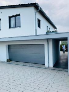 une maison blanche avec deux portes de garage dans l'établissement Larimar Apartment Kirchheim am Neckar, à Kirchheim am Neckar
