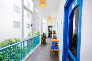 a balcony with a blue door and two stools at Tò Vò Hostel Huế in Hue