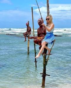 a woman sitting on a statue on the beach at Sandil Surf house in Ahangama