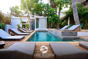 a swimming pool with chaise lounges and chairs in a resort at Casa Nudista - LGBT Hotel in Zipolite