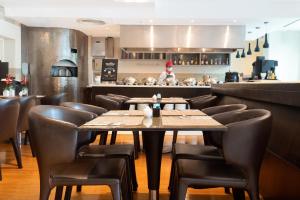 a restaurant with wooden tables and leather chairs at NH Bangkok Asoke in Bangkok