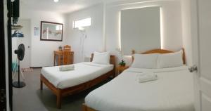 a bedroom with two beds with white sheets at Amor's Place in Puerto Princesa City