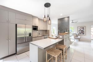 a kitchen with stainless steel appliances and white cabinets at Mango Wood Villa Tropical Coastal living in Clifton Beach