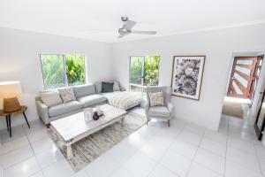 un soggiorno con divano e tavolo di Mango Wood Villa Tropical Coastal living a Clifton Beach