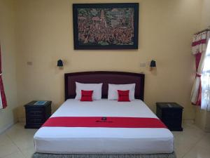 um quarto com uma cama grande e almofadas vermelhas em RedDoorz @ Puncak Tahura Hotel Bengkulu Tengah em Bengkulu