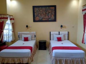 duas camas sentadas uma ao lado da outra num quarto em RedDoorz @ Puncak Tahura Hotel Bengkulu Tengah em Bengkulu