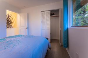 a bedroom with a blue bed and a window at Mauna Ua in Volcano