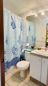 a bathroom with a toilet and a blue shower curtain at Cuatro Esquinas de Italia in La Serena