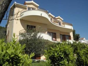 un gran edificio blanco con balcones y arbustos en Apartments Antonio, en Trogir