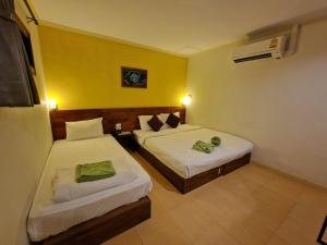 two beds in a room with yellow walls at Lemonade Boutique Inn in Ko Lanta