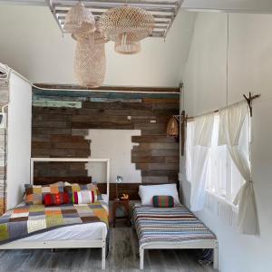 een slaapkamer met 2 bedden en een raam bij The 99 Cottage (บ้านทุ่งบางปลาม้า) in Suphan Buri