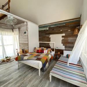 a bedroom with two beds and a wooden wall at The 99 Cottage (บ้านทุ่งบางปลาม้า) in Suphan Buri