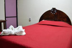 - un lit rouge avec une couverture rouge et un arc blanc dans l'établissement Hotel Casa Genesis, à Oaxaca