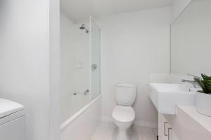 a white bathroom with a toilet and a shower at Astral Apartments. Spacious 2 bed, 2 bath apartment in a great location. in Melbourne