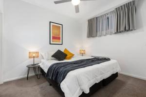 a white bedroom with a large bed with two lamps at Astral Apartments. Spacious 2 bed, 2 bath apartment in a great location. in Melbourne
