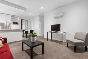 a living room with a red couch and a tv at Astral Apartments. Spacious 2 bed, 2 bath apartment in a great location. in Melbourne