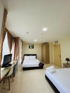 a hotel room with two beds and a desk at Noor Hotel Kangar in Kangar