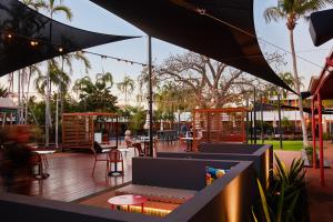 een patio met een tafel en stoelen en palmbomen bij The Continental Hotel in Broome