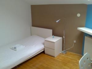 um pequeno quarto com uma cama branca e um candeeiro em Rainbow Rooms em Ljubljana