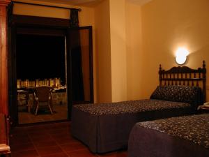 Schlafzimmer mit einem Bett und einer Tür, die zu einem Tisch führt in der Unterkunft Hotel Restaurante Baños in Baños de la Encina
