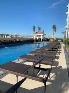 una fila de bancos junto a una piscina en SMDC Coast Residences Lovely Fully-furnished 1 BR Condo with pool, en Manila