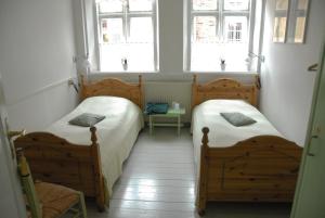 duas camas num pequeno quarto com duas janelas em Bed & Breakfast Hasse Christensen em Ribe
