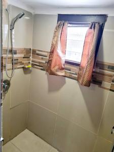 a bathroom with a shower with a curtain and a window at Masters 2 Bedroom Apartment Westfield in Nadi