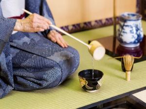 a person sitting on a bench cutting a piece of cloth at Imperial Hotel Tokyo in Tokyo