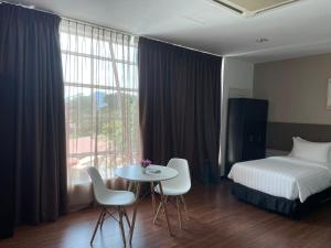 a hotel room with a bed and a table and chairs at King's Lane Ipoh in Ipoh