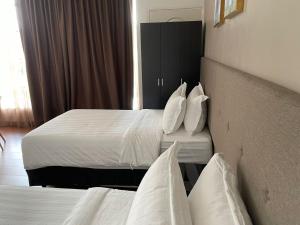 King's Lane Ipoh في ايبوه: غرفة فندقية بسريرين عليها شراشف ووسائد بيضاء