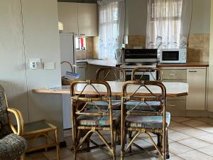 a kitchen with three chairs and a table and a counter at Margate Uvongo Seeskulp in Margate
