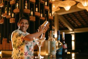 Ein Mann steht an einer Bar und hält ein Glas Wein. in der Unterkunft Club Hotel Dolphin in Negombo