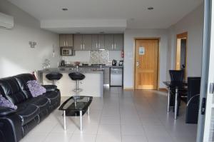 a living room with a black couch and a kitchen at Rocky Cape Retreat in Rocky Cape