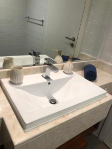 lavabo blanco en el baño con espejo en 2 Bedroom Deluxe Beach Apartment Al Marjan, en Ras al Khaimah