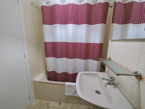 baño con lavabo y cortina de ducha roja y blanca en CASA PORTELA APARTAMENTOS, en A Revolta