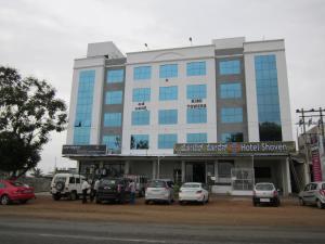a large building with cars parked in front of it at Hotel Shoven in Dāvangere