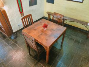 una mesa de madera con 2 sillas y un jarrón de flores. en Independent Mud House Studio (Large) with Kitchen en McLeod Ganj