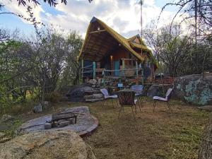 a log cabin with chairs and a fire pit at Otters' Haunt Eco Retreat in Parys