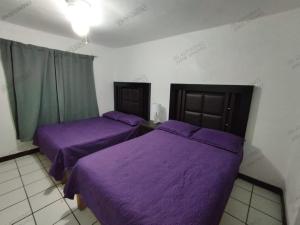 two beds in a room with purple sheets at Condominio 303 Loma Bonita, enfrente de la alberca! in San Carlos +7 photos