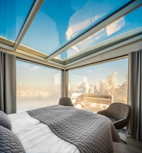 een slaapkamer met een groot raam met uitzicht op de bergen bij Ukkohalla Sky Cabin Glass Suite in Hyrynsalmi