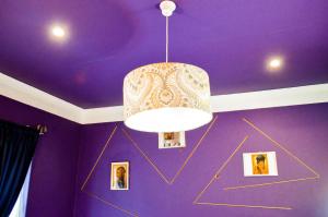 Habitación púrpura con lámpara de araña y fotografías en Mauya Guesthouse, en Kuilsrivier