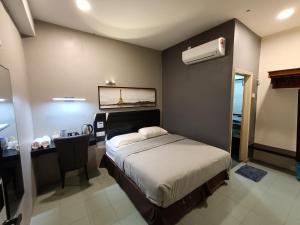 una camera da letto con un letto e una scrivania con aria condizionata di Winton Hotel a Mentekab Altre 12 foto