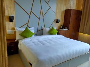 1 dormitorio con 1 cama blanca grande con almohadas verdes en Mountain view stay in Auli en Joshīmath