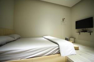 ein weißes Bett in einem Zimmer mit einem Flachbild-TV in der Unterkunft Walking Island in Xiaoliuqiu