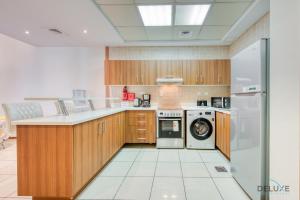a kitchen with wooden cabinets and a washer and dryer at Bright 1BR at Sulafa Tower Dubai Marina by Deluxe Holiday Homes in Dubai