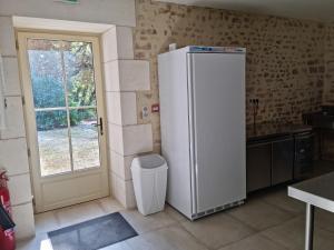 a white refrigerator in a kitchen with a window at Château de la Cressonnière in Antigny