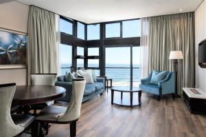 ein Wohnzimmer mit einem Sofa, einem Tisch und Stühlen in der Unterkunft Premier Hotel Cape Town in Kapstadt