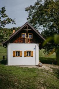 uma pequena casa branca com janelas com persianas de madeira em Kellerstöckl Berg 106 em Strem