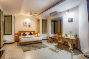 a bedroom with a bed and a desk and a table at Corbett Panorama Resort in Rāmnagar